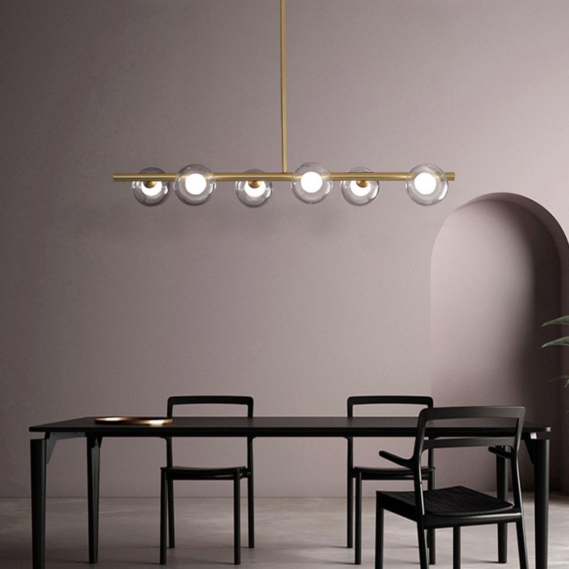 Gold six-globe pendant illuminated over a black dining table and chairs against a pale wall