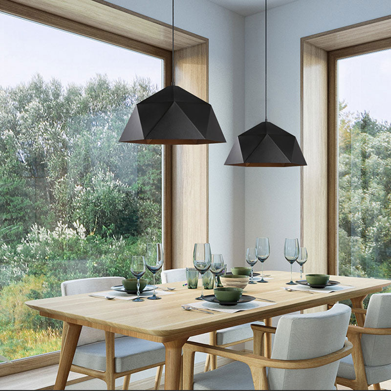 Two black faceted pendant lights above a wooden dining table beside large windows