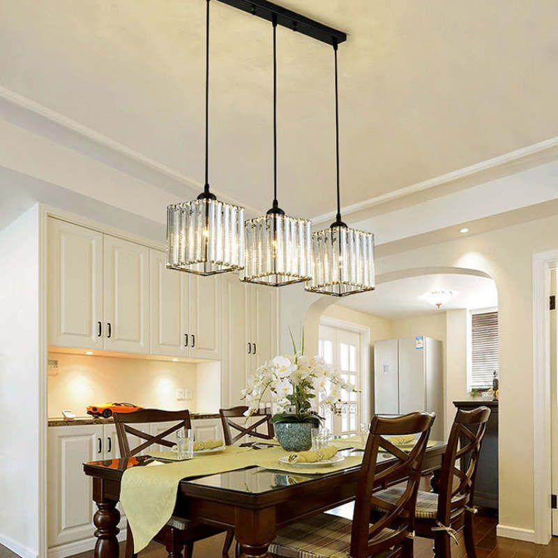 Three black Herbert square glass shades in a line beneath a rectangular canopy above a dining table with wooden chairs