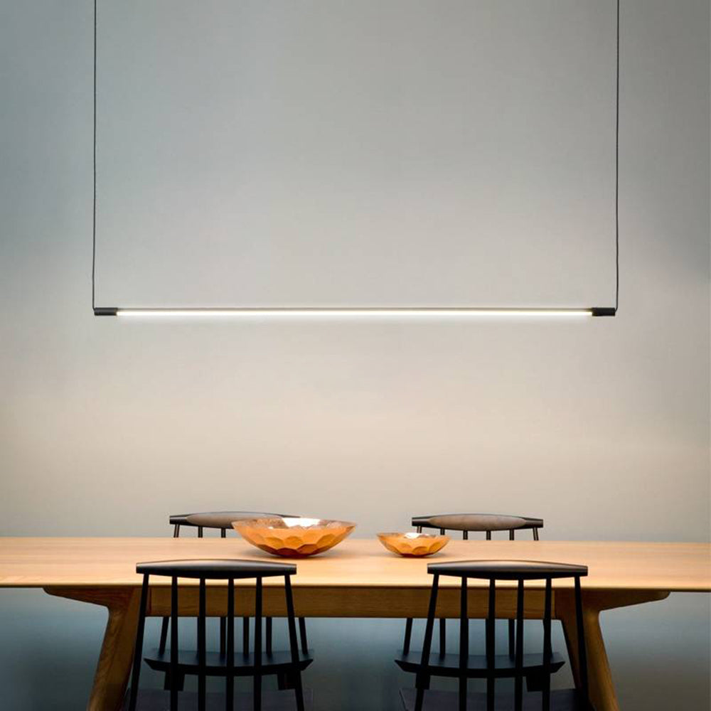 Slim black pendant above a wooden dining table with dark chairs.