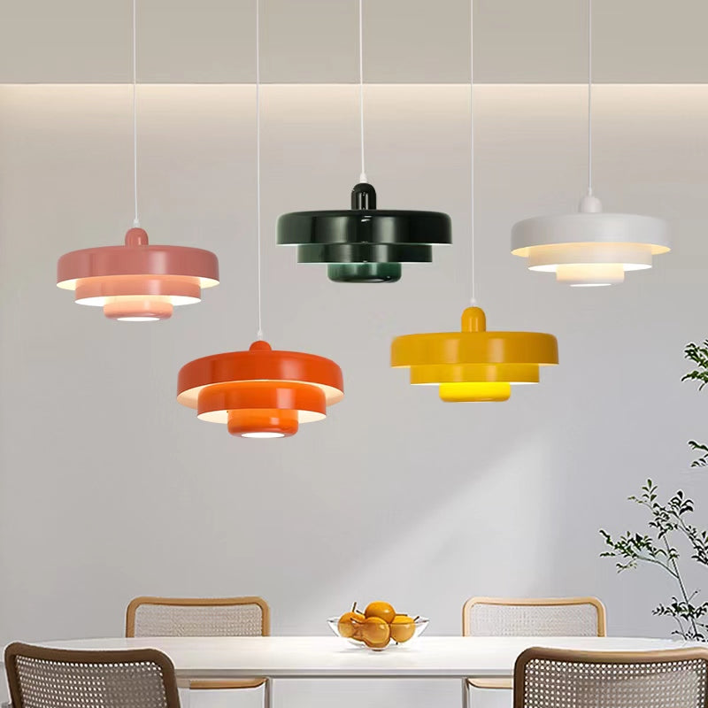 Pink, green, white, orange and yellow tiered pendant lights displayed above a dining table