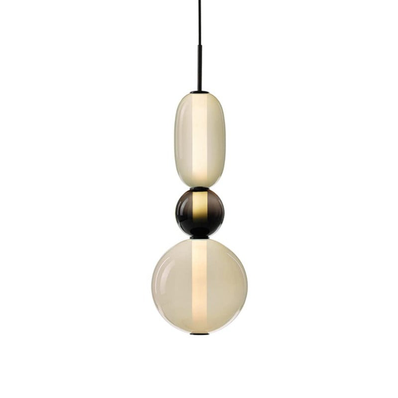 Three-form pendant with a pale capsule, small smoked globe and pale lower globe around a lit column