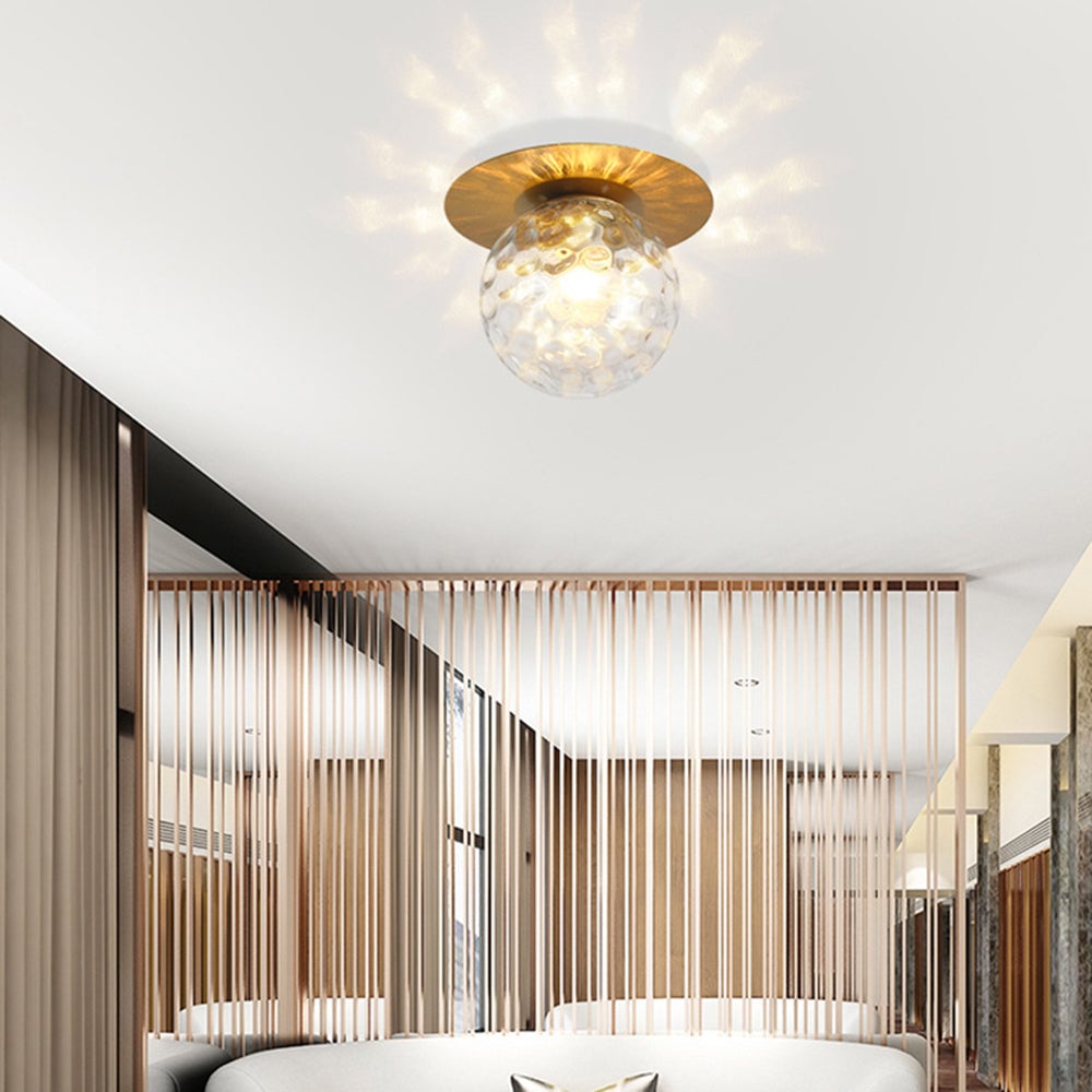 Clear textured glass globe beneath a brass-tone ceiling plate above a slatted room divider