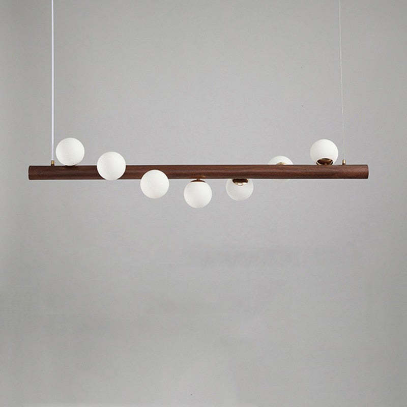 Dark wooden bar pendant with seven unlit White globes staggered above and below the bar against a Gray background