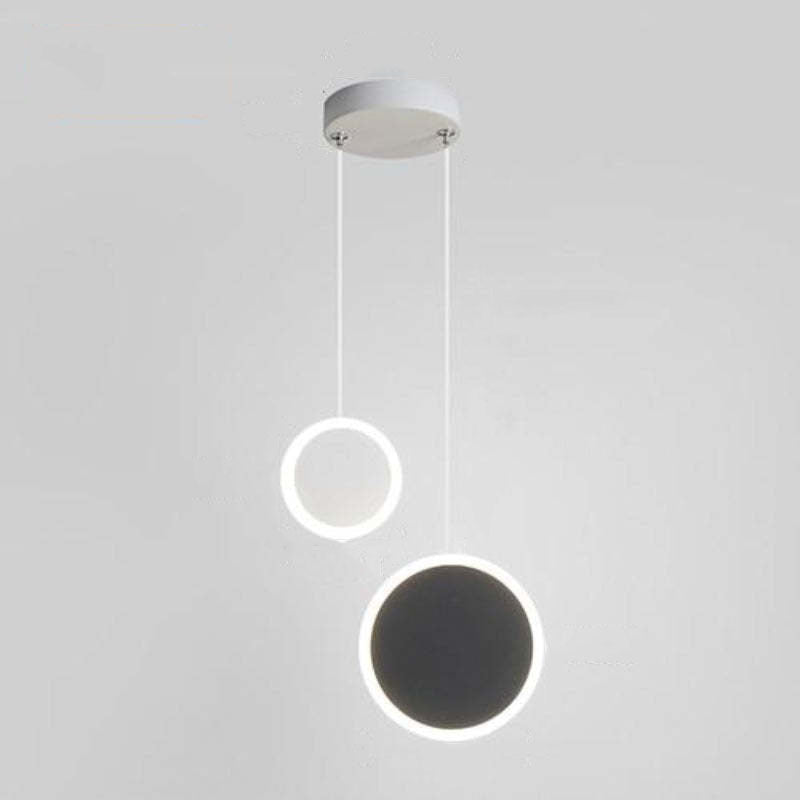 Small white circular element and larger black-faced circle on separate drops from a shared white canopy