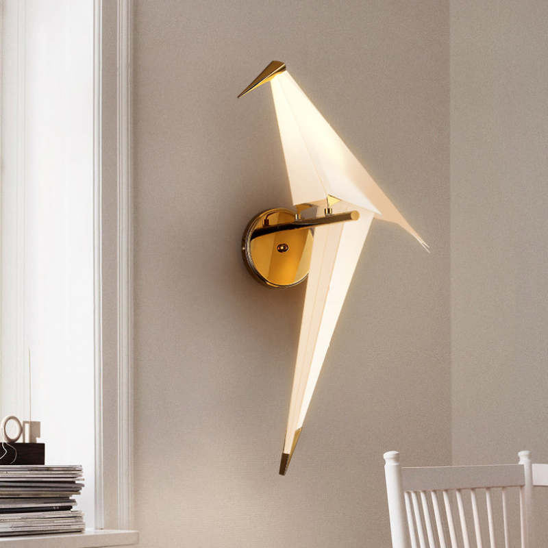 Single illuminated Clifford bird beside a window, books and white chair on a pale wall