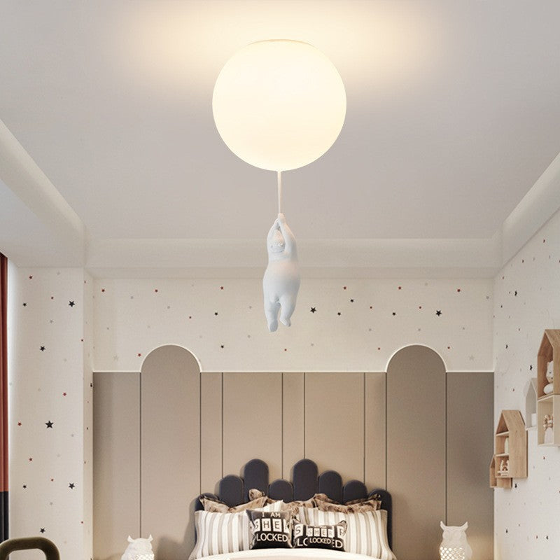 Style C bear hanging beneath a lit ceiling globe above a bedroom bed