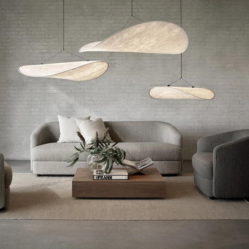 Grouped curved white pendants above a gray sofa against a pale brick wall