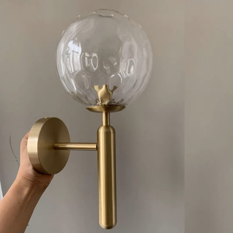 Hand-held gold-tone fitting with a transparent rippled globe