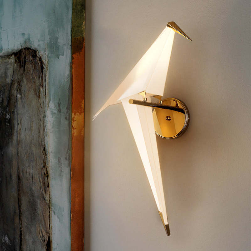 Single-bird Clifford wall light with round gold-tone plate near an abstract artwork