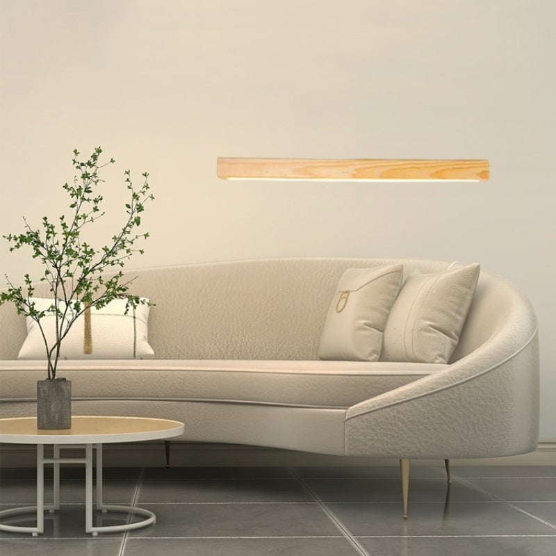 Pale wood-grain Ozawa wall light above curved cream sofa with cushions and plant on round coffee table