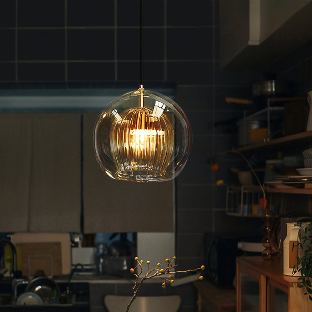 Single warm-lit globe pendant above an indoor counter with shelves