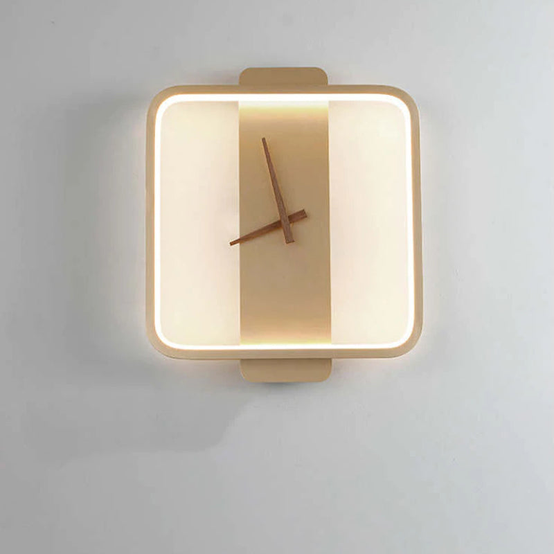 Gold rounded-square wall light with warm-looking inner outline, vertical backplate and Brown hands against a Gray wall