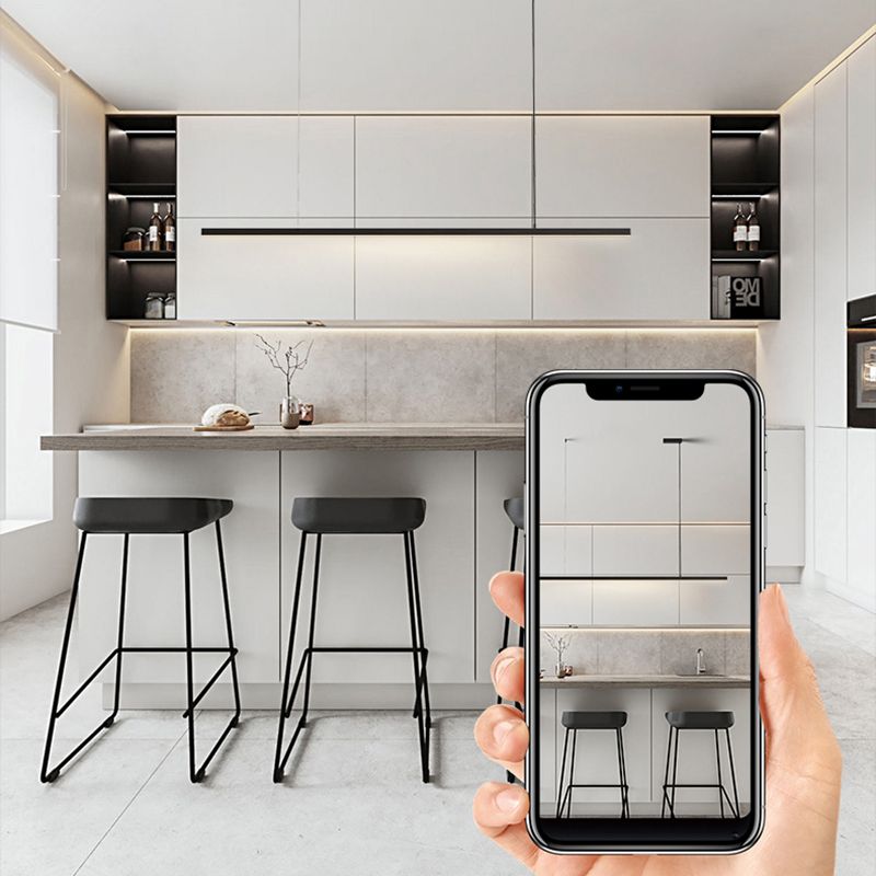 Black Edge linear pendant above kitchen island and stools, with a hand holding a phone displaying the room