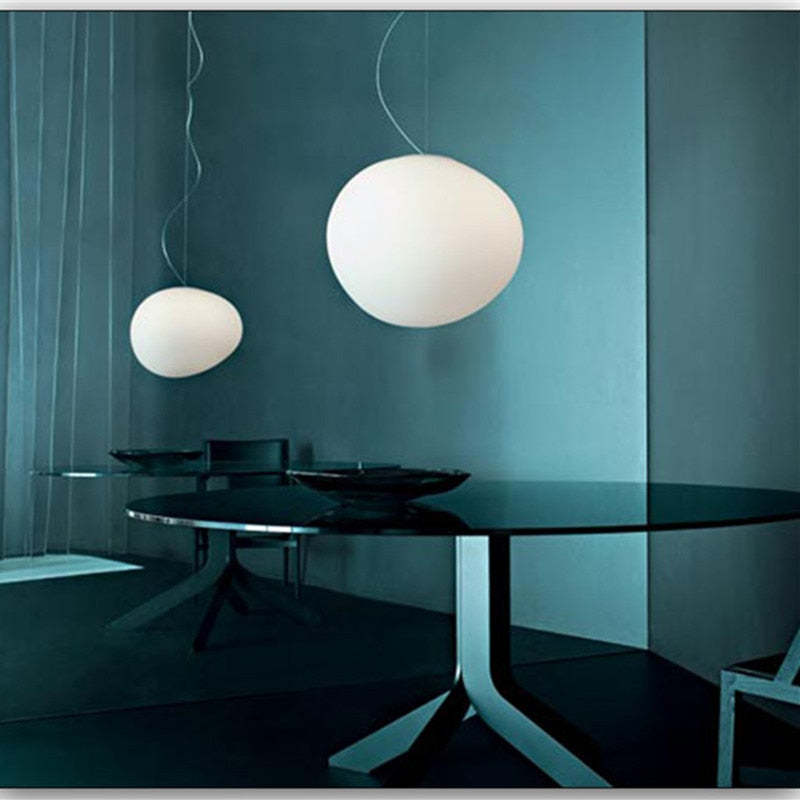 Two white glass pendants above a blue-green dining area