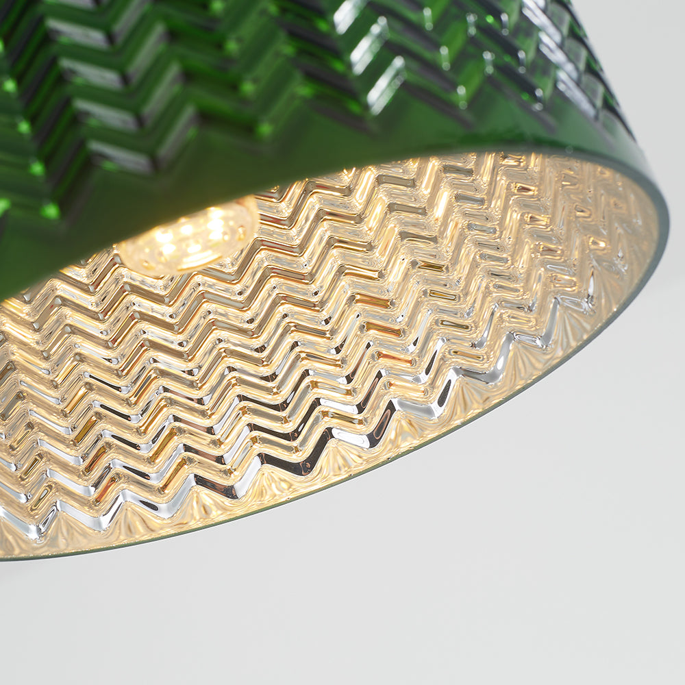 Close underside of textured green glass shade with a clear chevron surface and partly visible illuminated bulb
