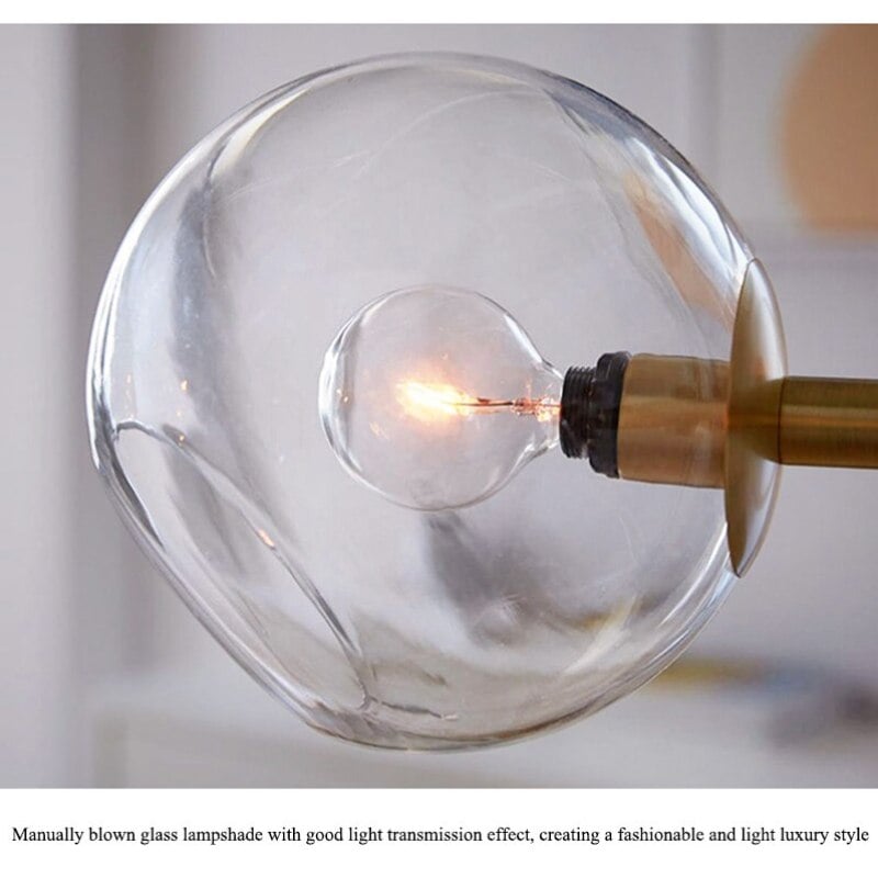 Close clear open glass globe with lit bulb and gold support, with caption describing manually blown glass
