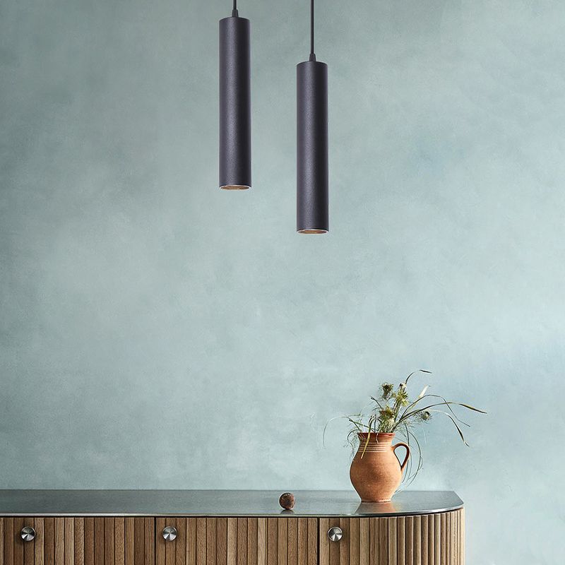 Two black Edge cylinder pendants above a cabinet with a plant.