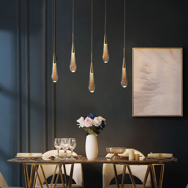 Five Hailie clear teardrop pendants at staggered heights above a dining table with flowers and tableware