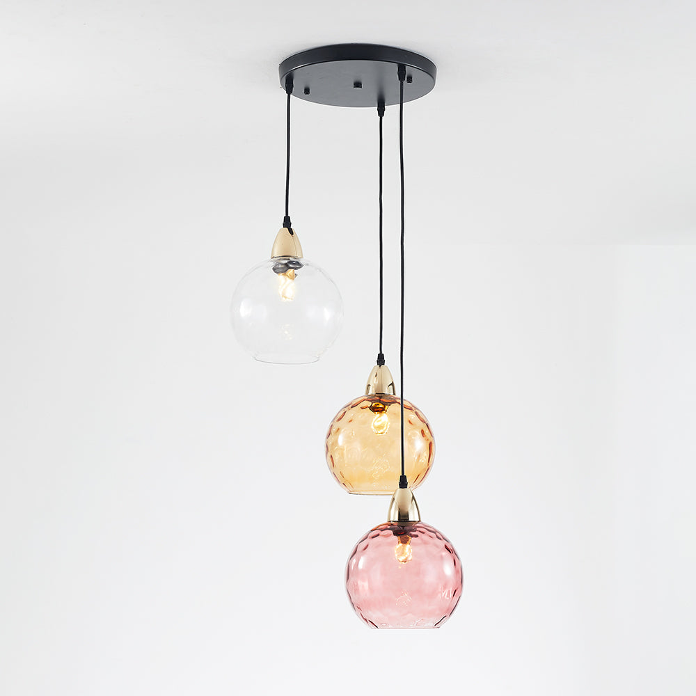 Clear, amber and pink glass globes in a staggered arrangement below a black circular canopy