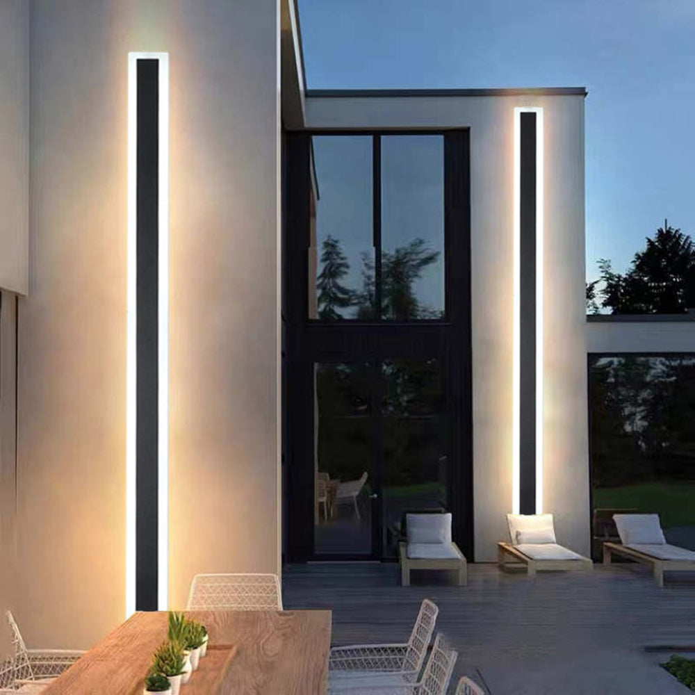 Tall Edge wall lights on patio columns beside an outdoor dining table and lounge chairs