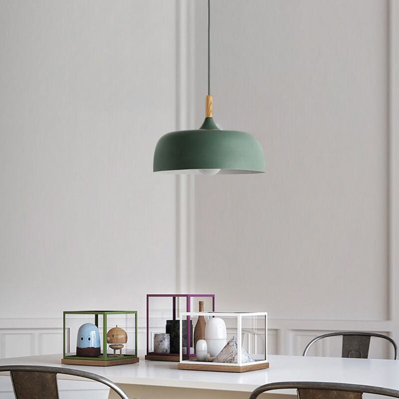 Green deep dome pendant over a white dining table with display boxes against a paneled wall