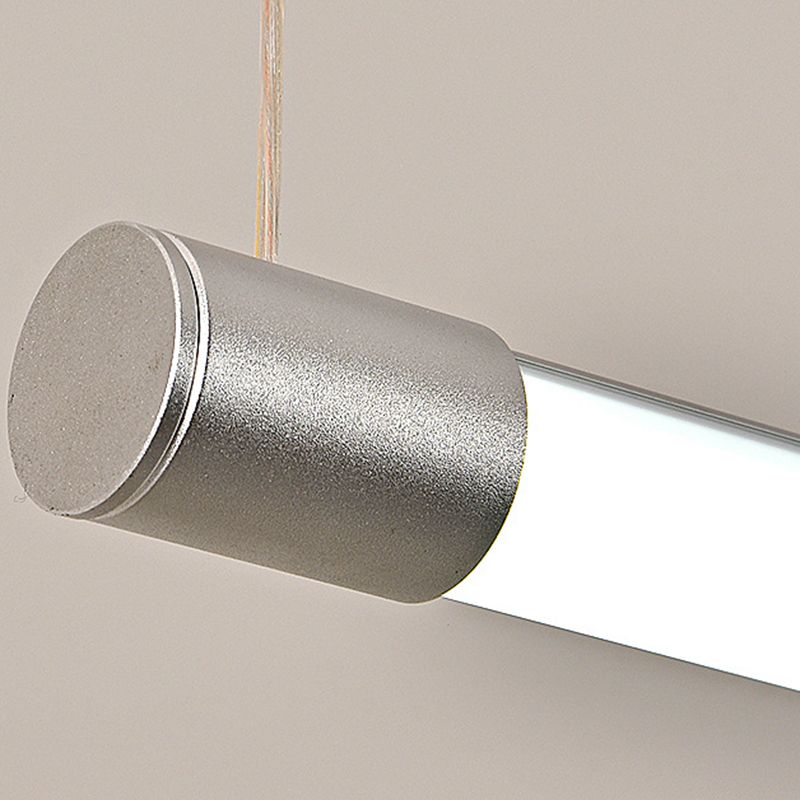 Close-up of a silver cylindrical endcap and suspension wire beside the luminous bar