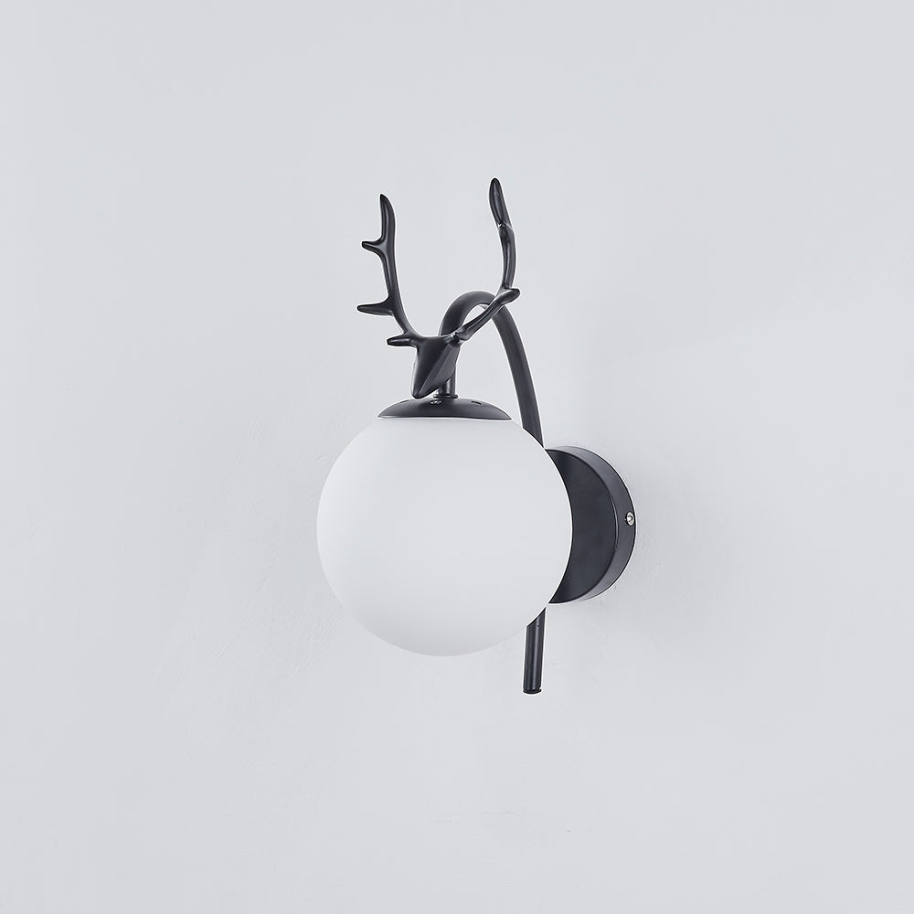 Black deer-head wall light with an unlit white globe and round backplate on a pale wall