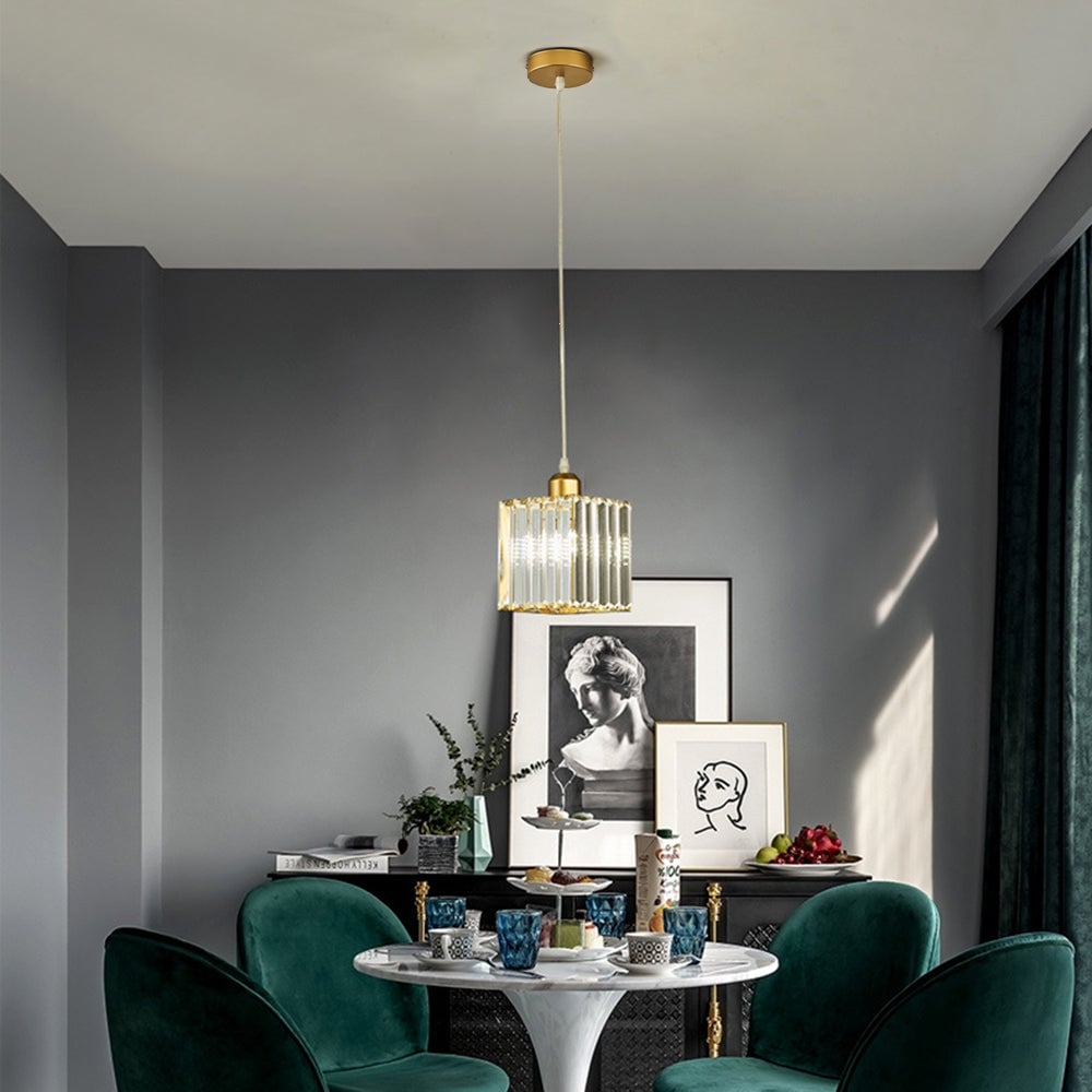 Single gold square glass-bar pendant above round table and green chairs, with framed bust and portrait artwork behind