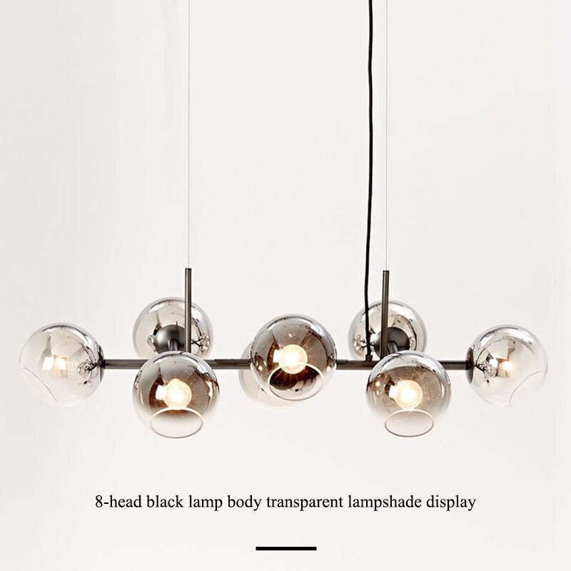 Black bar pendant with darker reflective globes and lit bulbs, caption describing eight heads and transparent shades