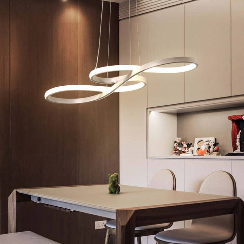 Gold crossing-loop pendant above a wood dining table