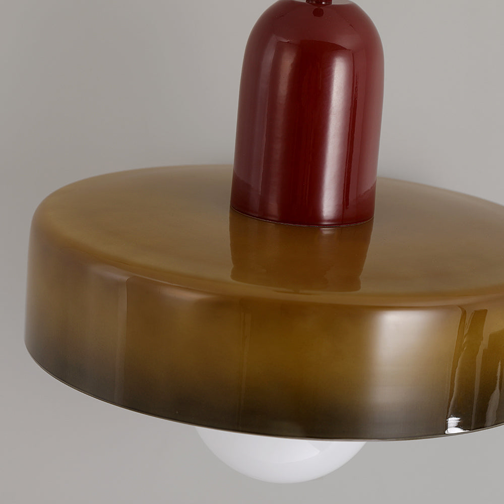 Close-up of a red-brown cylindrical centre above an olive-green glass ring with the white globe visible below