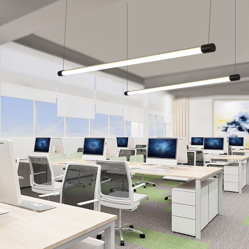 Two black-ended linear tube pendants above rows of office desks and computers
