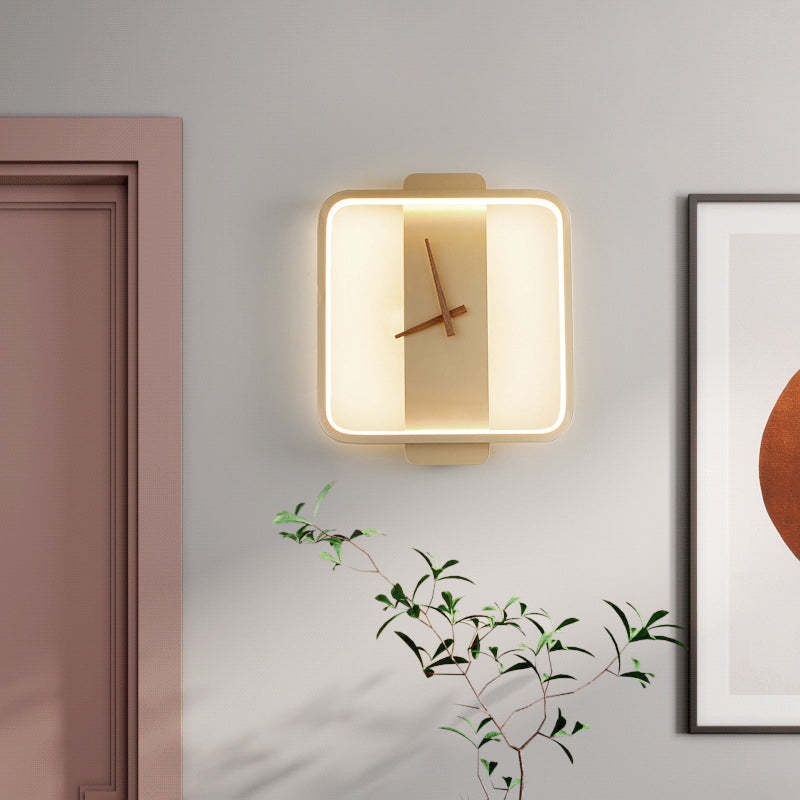 Lit rounded-square gold-tone Nielsen clock-face wall light beside a door frame and framed artwork