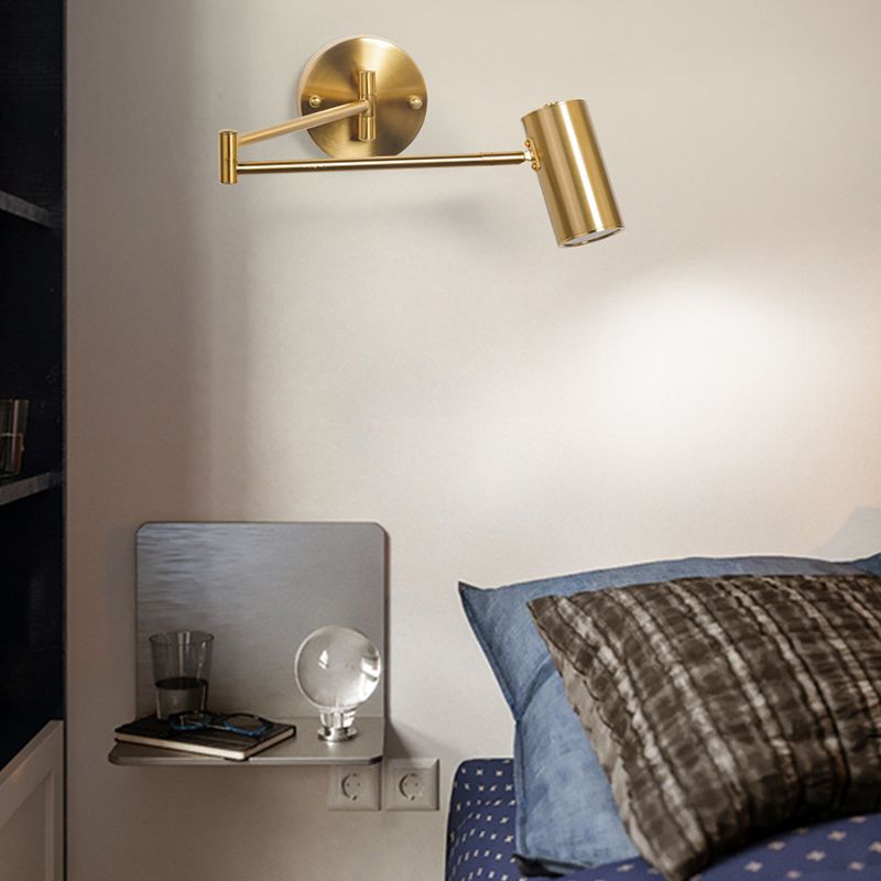 Freja Gold-style cylindrical shade and articulated arm above a bed and small shelf