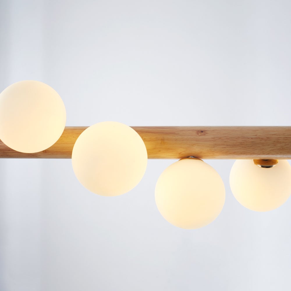 Close-up of warm-looking White glass globes and Gold-tone collars around a light wood bar