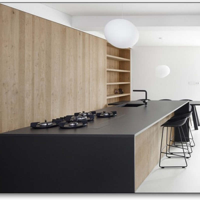 White egg pendant above a dark kitchen island with another pendant further back and wood cabinets along the wall