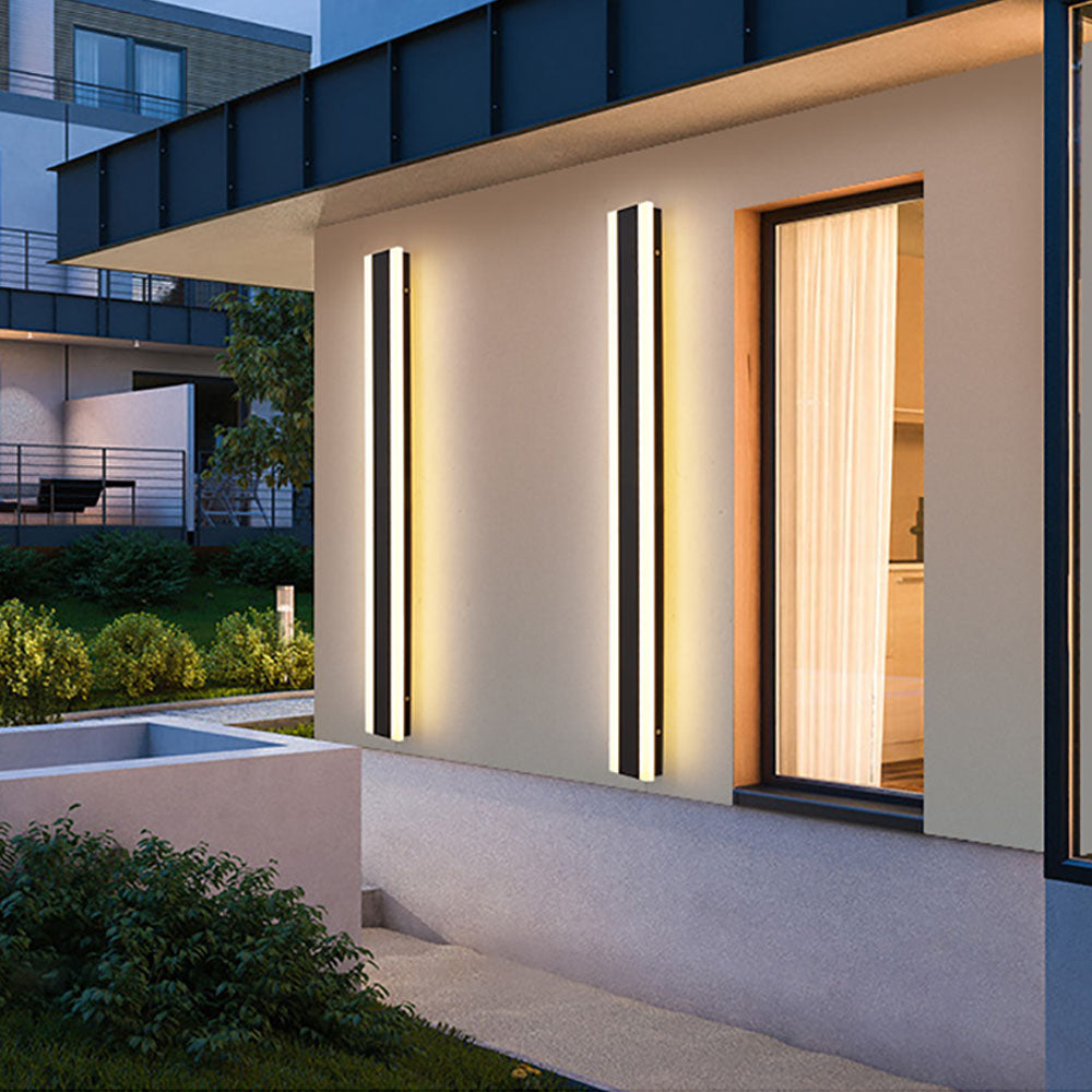 Two Black Orr wall-light bars with warm white edge glow beside an exterior window
