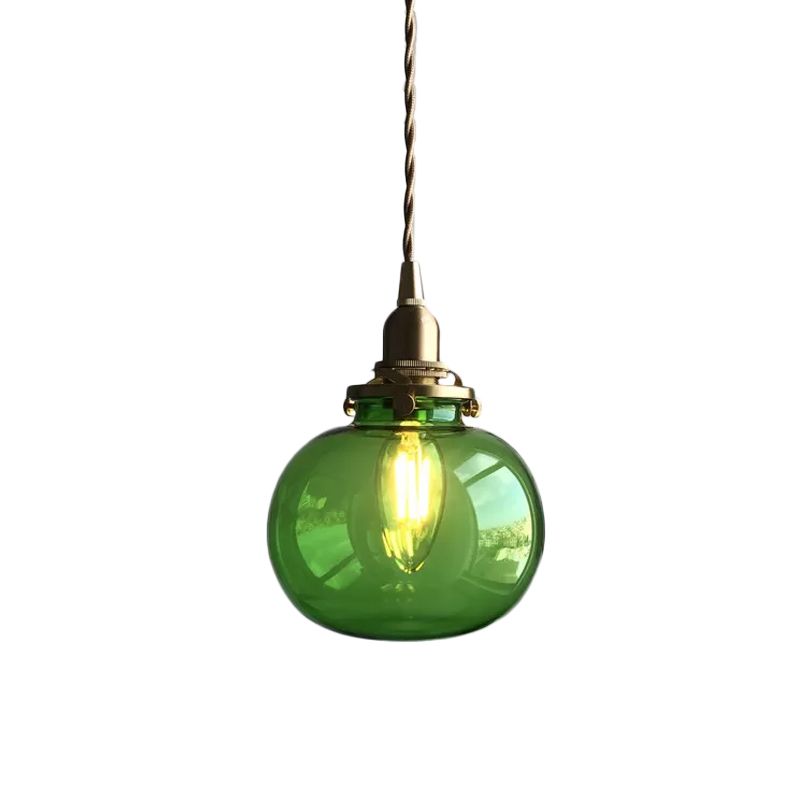 Green transparent glass globe pendant against a pale wall