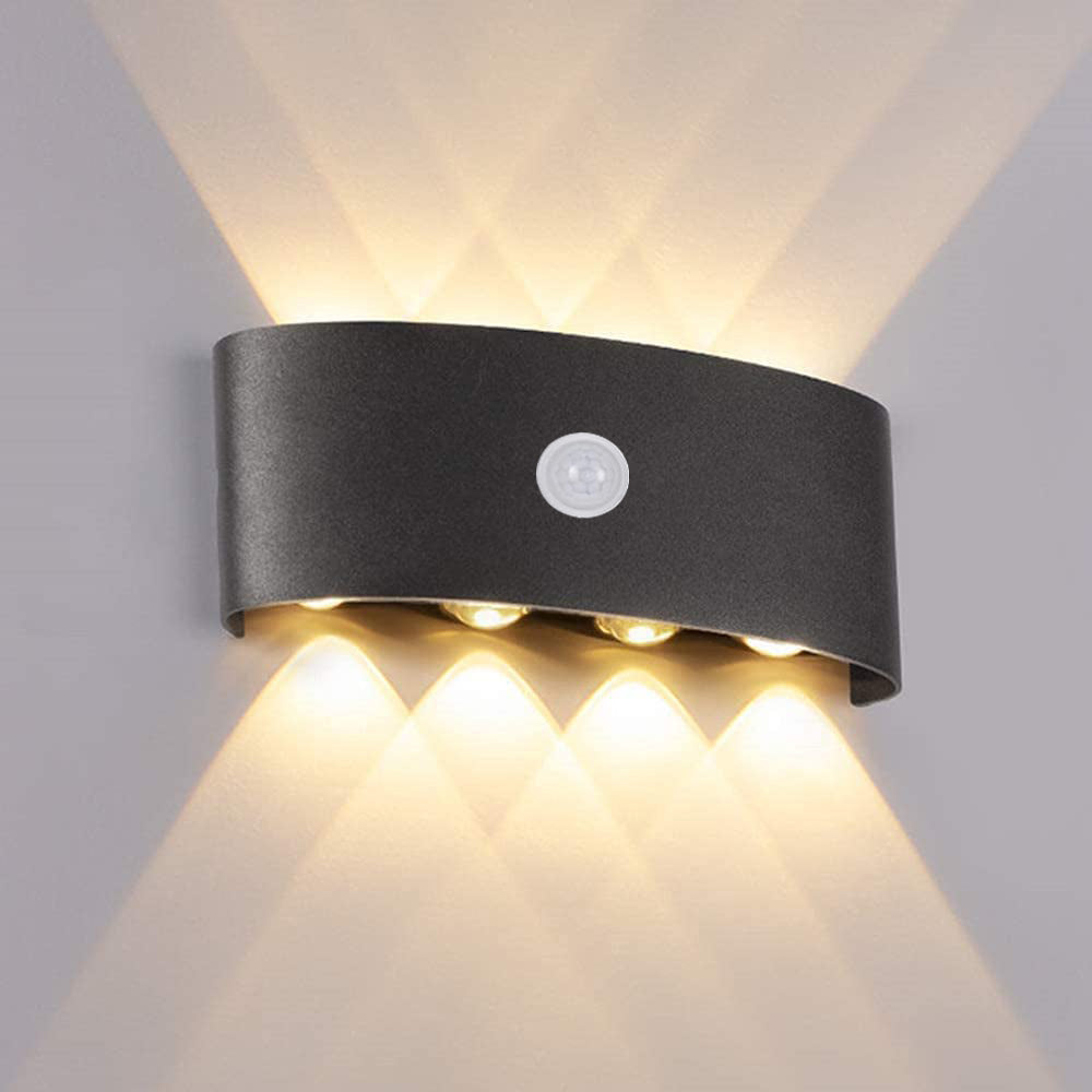 Black curved wall light with a central round lens casting warm-looking upward and downward beams