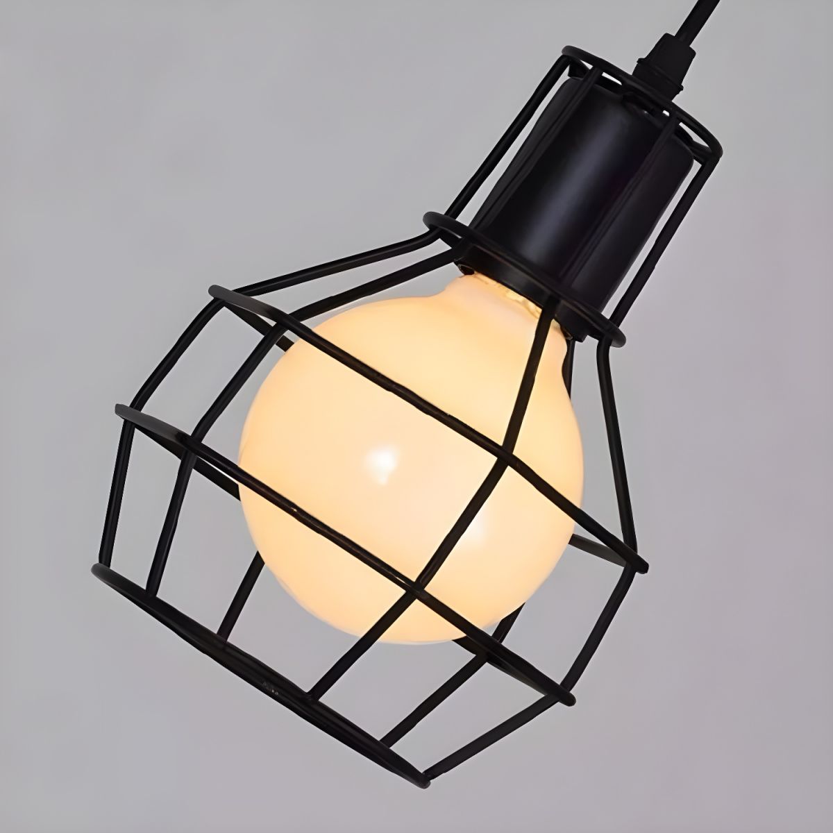 Close view of an Alessio black wire cage surrounding a pale bulb