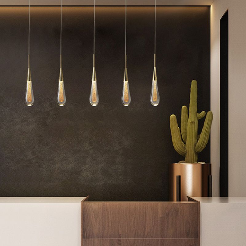 Five Hailie clear teardrop pendants in a row above a cabinet beside a cactus