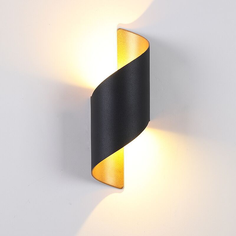 Close view of a black curved wall light with gold-tone interior and upper and lower wall glow
