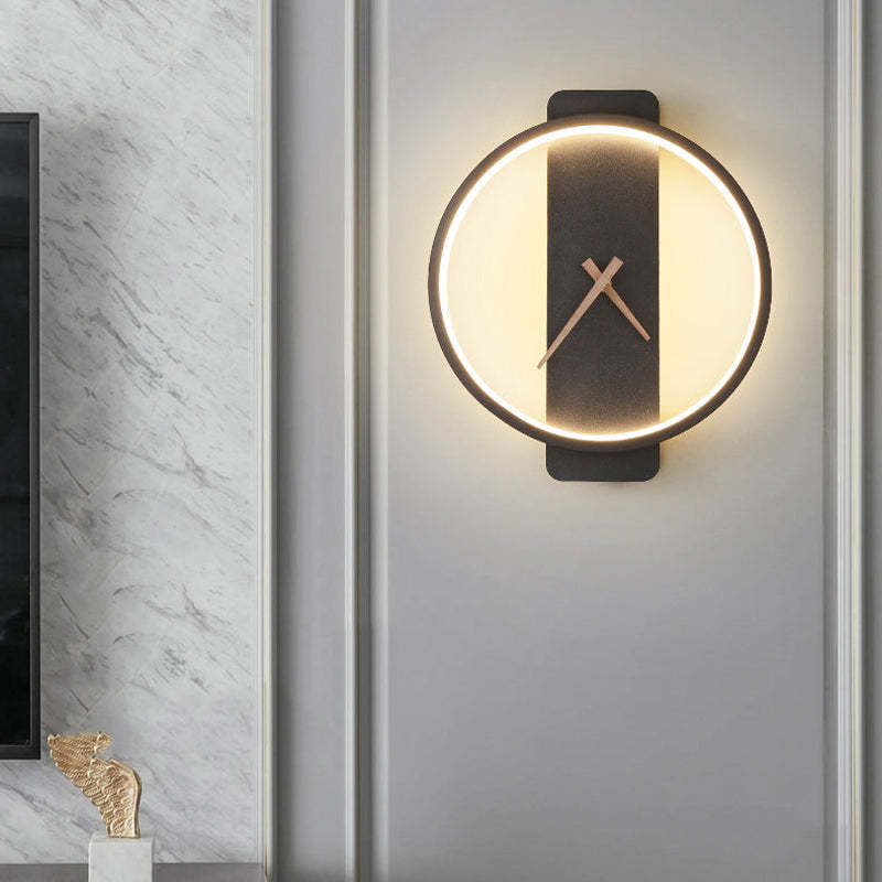 Lit round black Nielsen clock-face wall light beside a marbled TV wall and a small sculpture