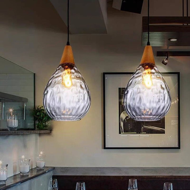 Two wide clear Avi pendants with oval glass texture above dining counter near framed artwork