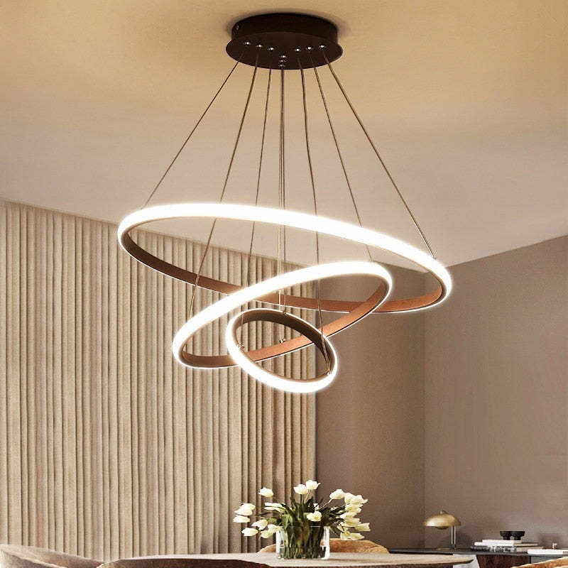 Coffee Brown three-ring pendant light above a dining table with White flowers, closed curtains and Gold dome table lamps
