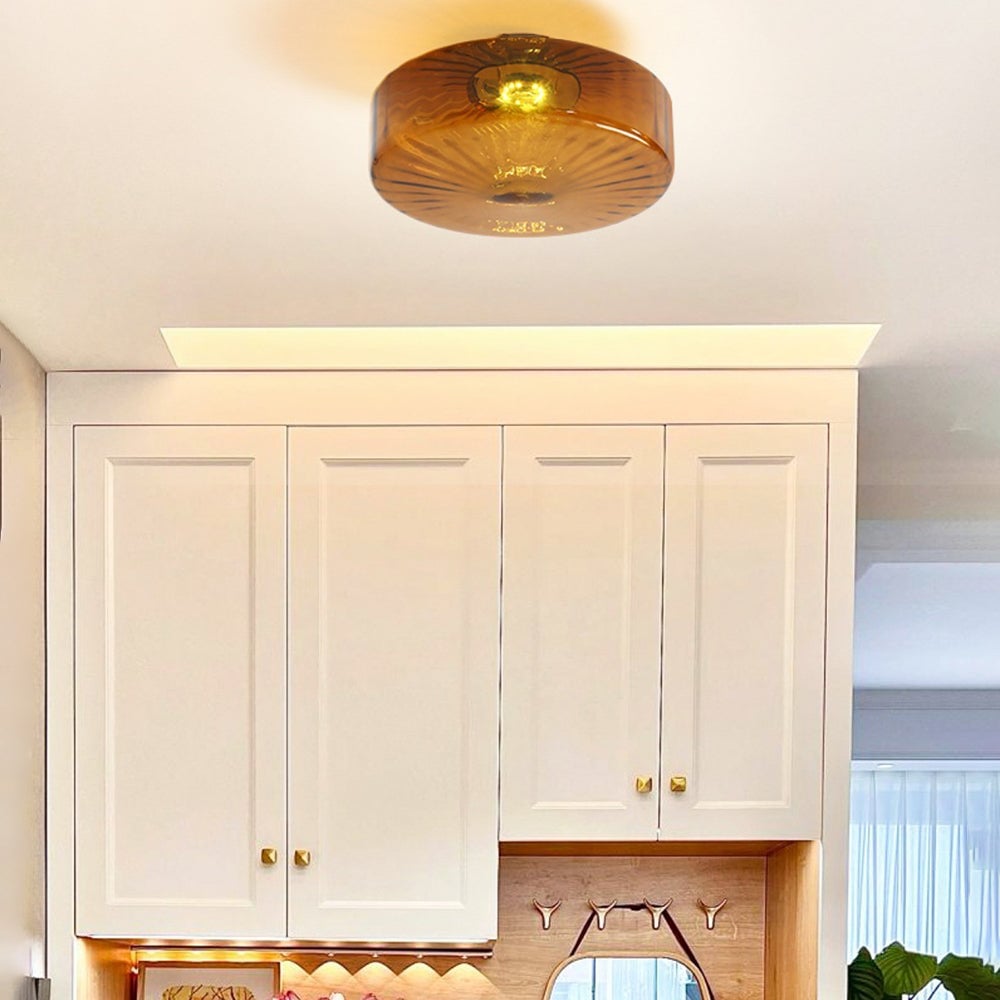 Lit Hailie brown drum ceiling light above white kitchen cabinets