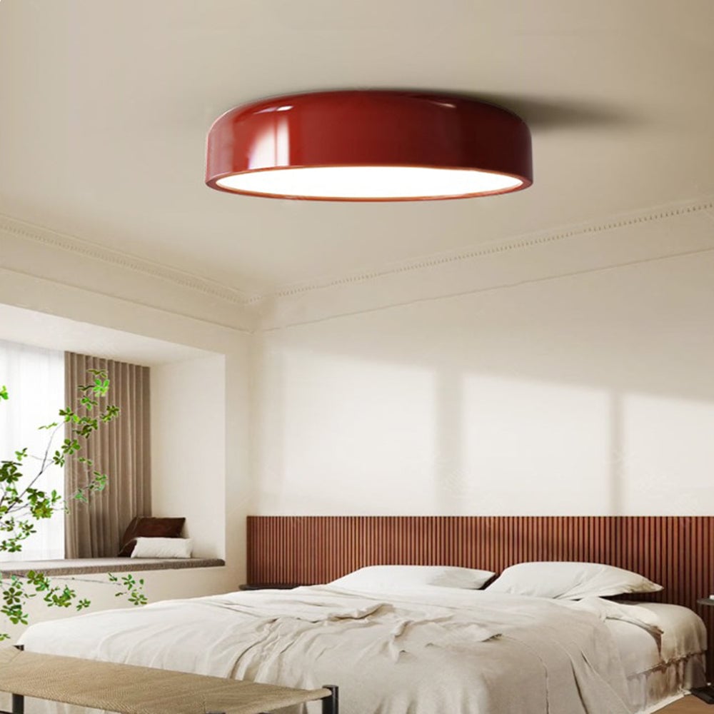 Red Morandi ceiling light above a bed with a wooden headboard