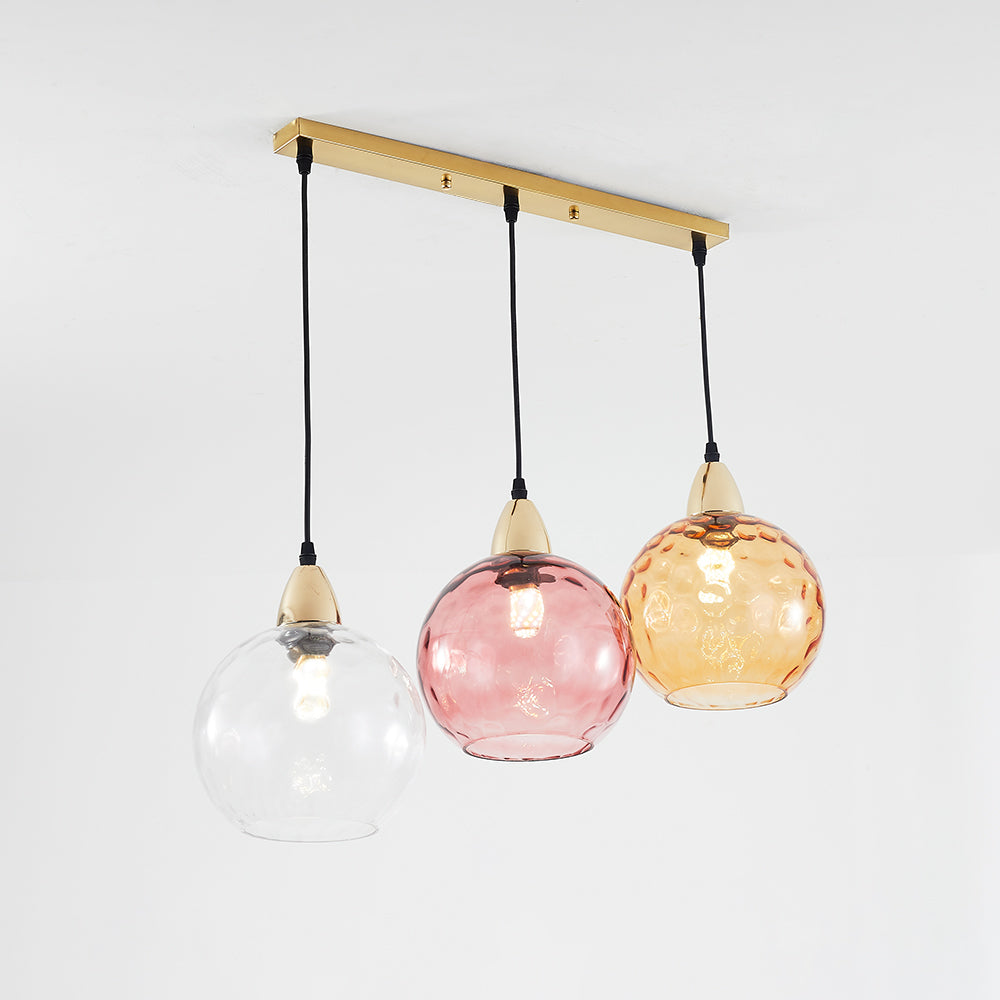 Angled view of a gold-tone straight canopy with clear, pink and amber globes at different drops