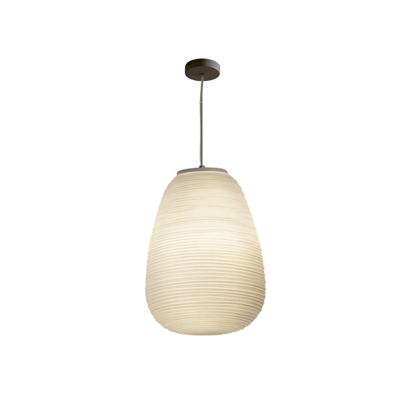 Tall tapered ribbed white pendant illuminated on a white background with dark canopy and cord